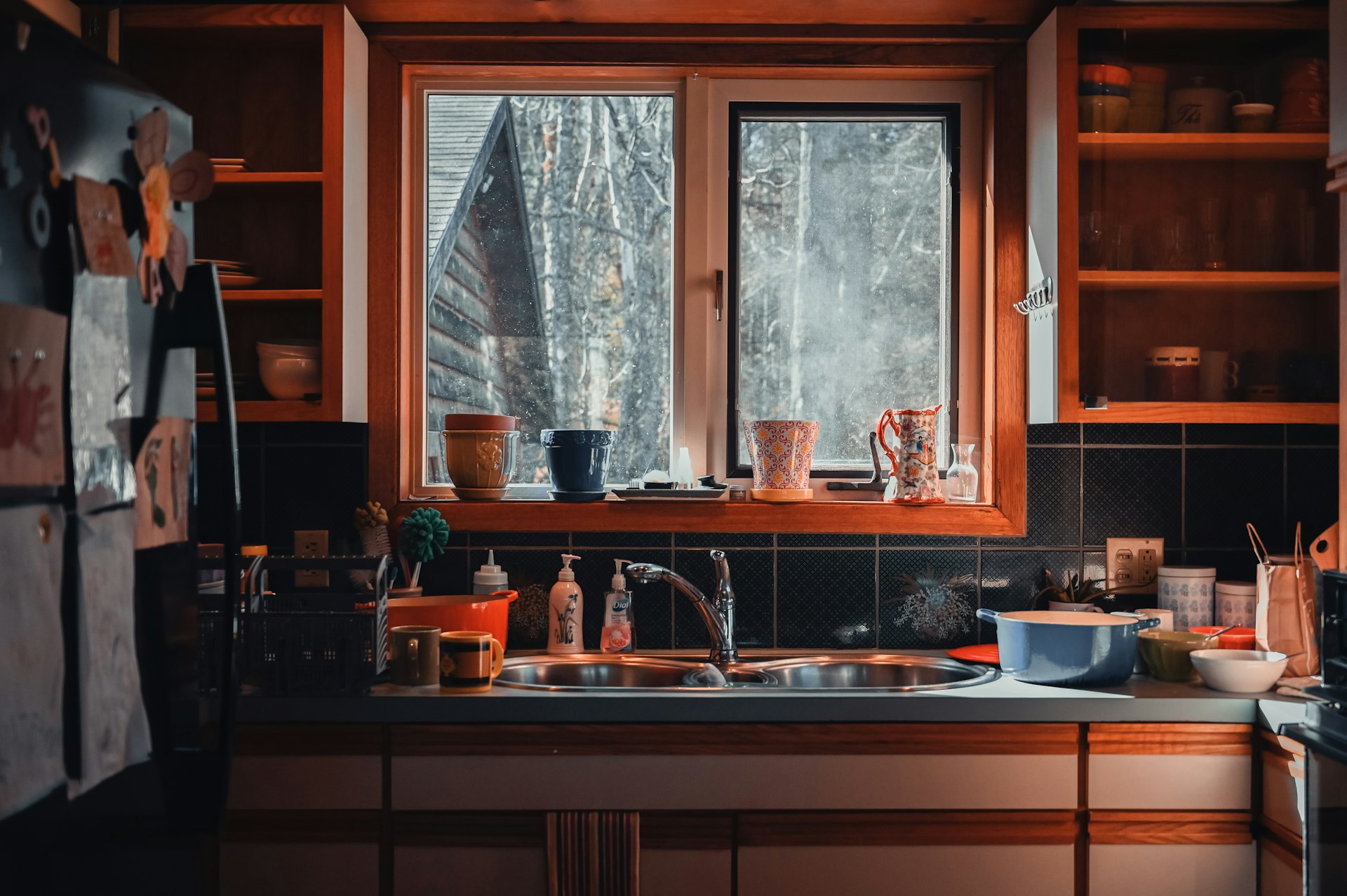 A kitchen filled with lots of clutter next to a window